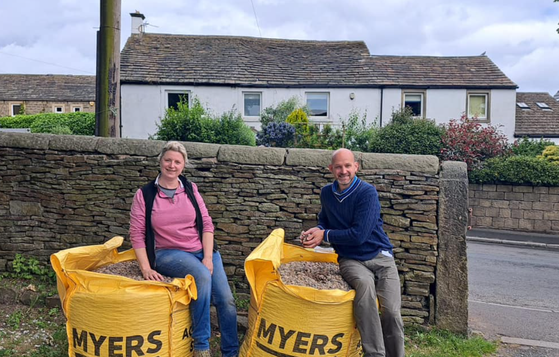Two people beside bags of Myers aggregate for the graveyard work.